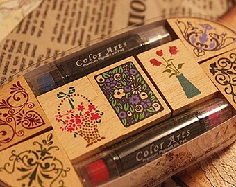May include: A set of six wooden stamps with various floral and decorative designs. The stamps come with two ink pads, one black and one red. The ink pads are labeled "Color Arts Premium Pigment Ink Pad".