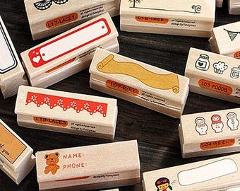 May include: A collection of wooden stamps with various designs, including lace, a tree, a scroll, food, dolls, and a thought bubble. The stamps are all rectangular and have a red and white border. The text on the stamps includes "L17-LACE1", "LT2-TREE", "L79-LACE3", "107-ROLL", "L03-FOODS", "L04-9프로시카", and "LOD-THINK".