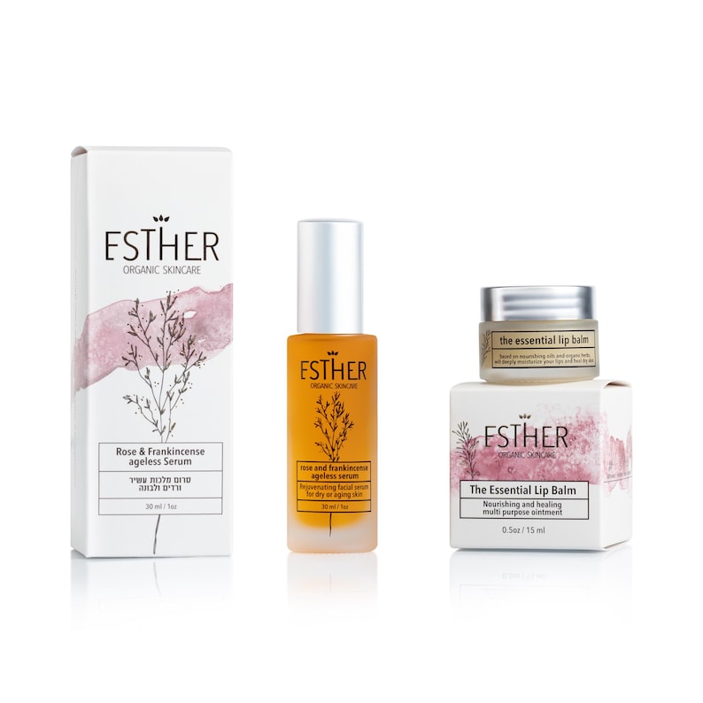 Puede incluir: Una caja blanca y un frasco de vidrio &aacute;mbar a juego de s&eacute;rum antiedad Rose & Frankincense de Esther Organic Skincare, junto a una caja peque&ntilde;a blanca y un tarro de cristal de The Essential Lip Balm, ambos con ilustraciones bot&aacute;nicas y rosas.