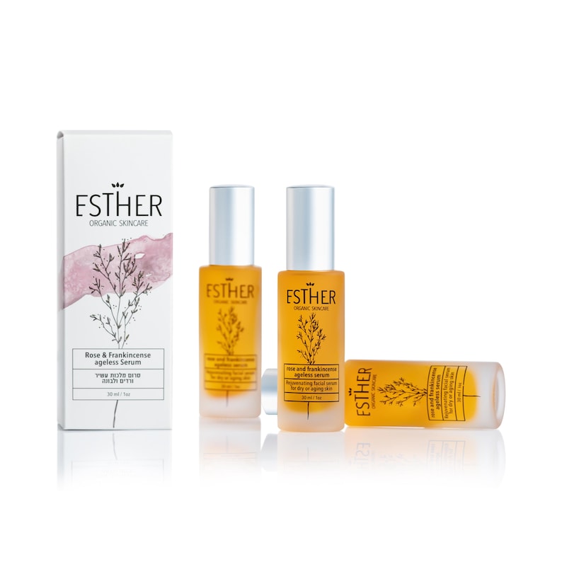 Puede incluir: Tres frascos de vidrio &aacute;mbar de suero antiedad Rose & Frankincense de Esther Organic Skincare, de 30 ml cada uno, junto a una caja rectangular blanca con una ilustraci&oacute;n bot&aacute;nica, un toque de acuarela rosa y la marca Esther.