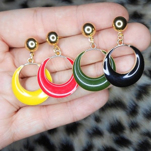 Op de afbeelding: Vier paar gouden creolen met verschillende gekleurde emaille. De oorbellen zijn geel, rood, groen en zwart.