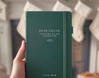 Puede incluir: Un diario de tapa dura en color verde oscuro con una banda elástica de cierre. La portada presenta texto en blanco que dice DEAR CHLOE, LETTERS TO MY DAUGHTER, un pequeño gráfico de hoja y el texto LOVE, MOM en la parte inferior.