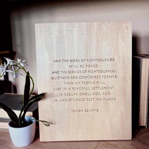 May include: A wooden sign with the text "AND THE WORK OF RIGHTEOUSNESS WILL BE PEACE. AND THE SERVICE OF RIGHTEOUSNESS, QUIETNESS AND CONFIDENCE FOREVER. THEN MY PEOPLE WILL LIVE IN A PEACEFUL SETTLEMENT, IN SECURE DWELLINGS, AND IN UNDISTURBED RESTING PLACES ISAIAH 32:17-18"