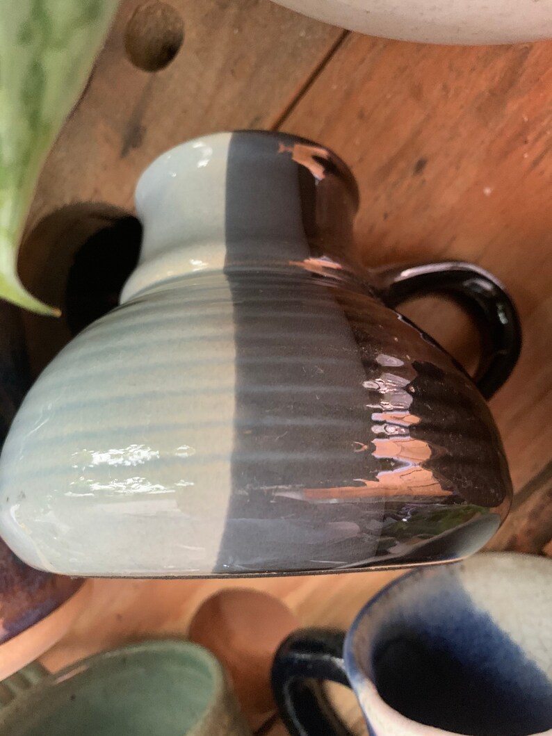 May include: A ceramic mug with a light blue and dark grey glaze. The mug has a handle and a rounded shape.