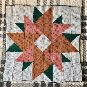 May include: A crocheted blanket with a star pattern in shades of white, green, pink, and brown.