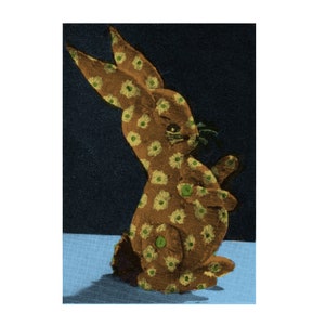 May include: A brown stuffed rabbit with a yellow and green floral pattern. The rabbit is sitting on a blue surface.