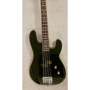 May include: A black electric bass guitar with a glossy finish. The headstock is black with the brand name "Charvette" in white. The fretboard has white dot inlays. The bass has four strings and chrome hardware.