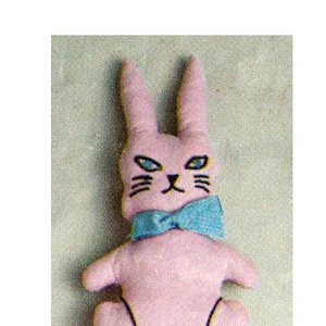 May include: A pink plush bunny rabbit with black eyes and a blue bow tie. The bunny has a white tail and black stitching around its feet.