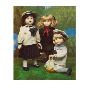 May include: Three porcelain dolls dressed in sailor outfits. The dolls are standing on a green grassy surface. The doll on the left is wearing a white sailor shirt with a black and blue collar, a black skirt, and a straw hat. The doll in the middle is wearing a black sailor shirt with a red and white collar and a black skirt. The doll on the right is wearing a white sailor shirt with a blue and white collar, blue and white striped pants, and a blue and white sailor hat. The doll on the right is holding a small yellow sailboat.