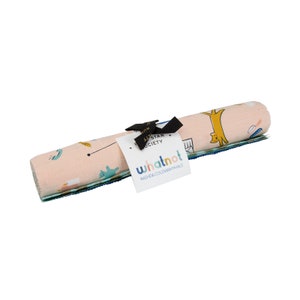 May include: A rolled up set of three pink, blue and green fabric squares with a whimsical pattern of animals and objects. The fabric is labelled "whatnot RAGHDA COLEMAN VINHALE" and "The All Star Society".