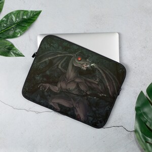 May include: Laptop sleeve featuring a dark grey creature with red eyes and wings, set against a dark green forest background.