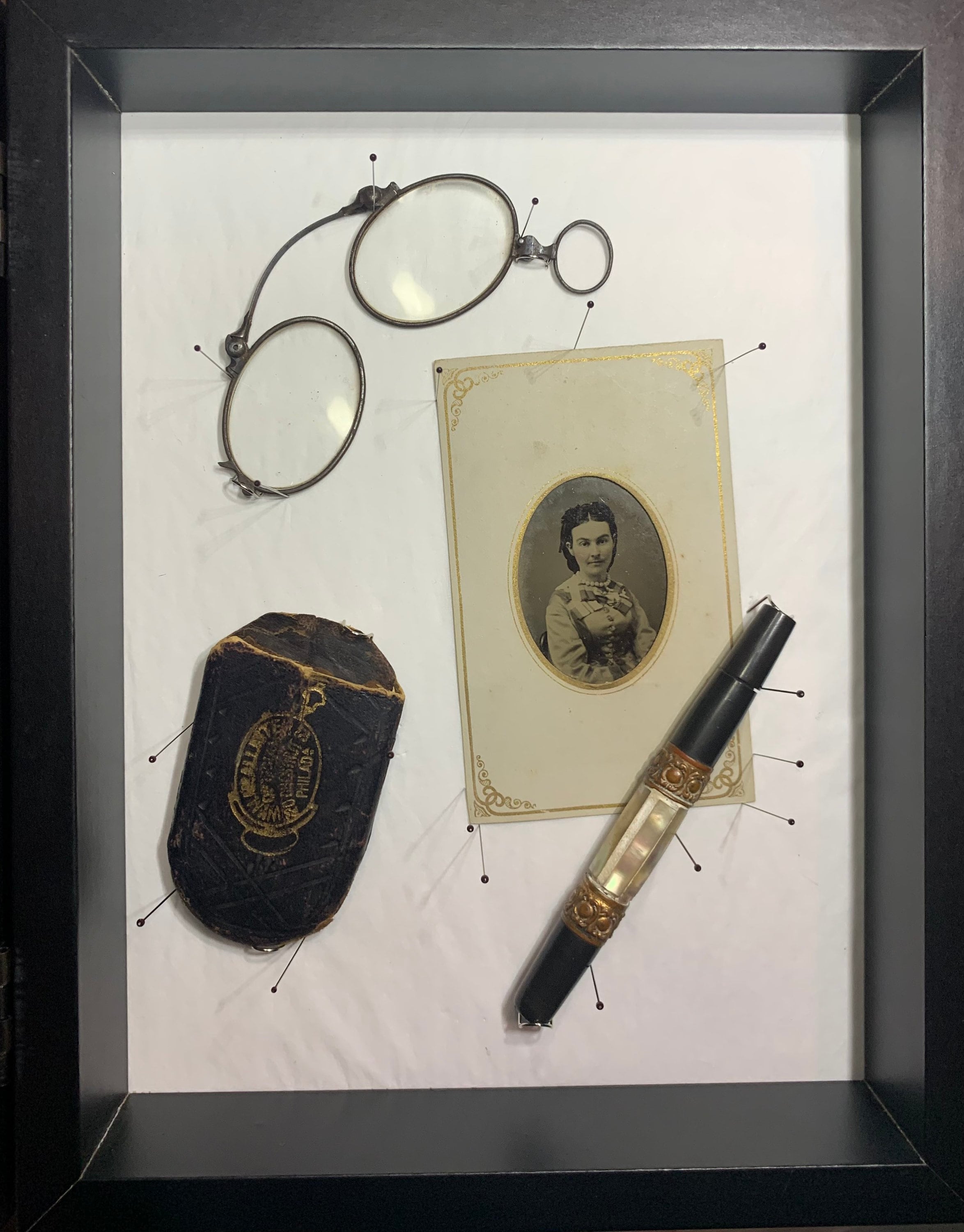 Victorian folding glasses, needle case, and civil war tintype in a museum archive display. 19th century shadowbox