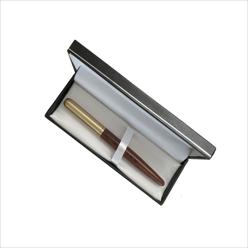 May include: A brown and gold pen with the word "Schreib" on it, in a black pen case with a white interior.
