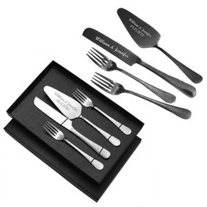 May include: A set of cake serving utensils, including a server, knife, and forks, presented in a black box. The server and knife are engraved with names and a date. The forks have "Mr." engraved on them. The utensils have a textured handle.