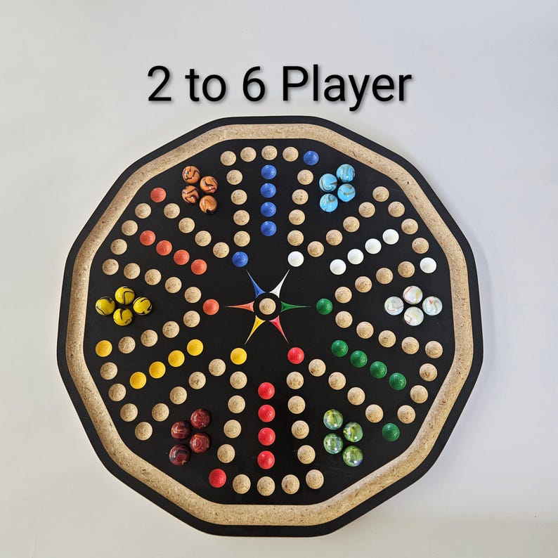 May include: An octagonal board game with the text 2 to 6 Player, featuring a black surface with circular indentations arranged in a star pattern. The board includes sets of colored marbles in orange, blue, white, green, red, and yellow.