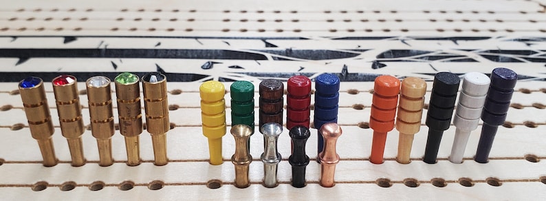 May include: A set of 18 colorful wooden pegs with different colored tops, including blue, red, green, yellow, orange, brown, black, white, and silver. The pegs are arranged in a row on a wooden board.