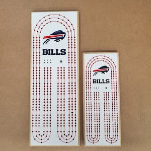 May include: Two wooden game boards with red and white circles and a blue and red Buffalo Bills logo. The larger board is 18 inches tall and the smaller board is 12 inches tall. Both boards have the text "BILLS" printed on them.