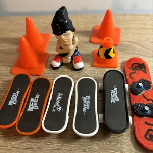 以下が含まれることがあります： ミニチュアの指スケートボードとスノーボードのコレクション。Tech Deckブランドのボード4枚、Blindブランドのボード1枚、赤いスノーボードが含まれています。また、無地のオレンジ色の交通コーン3個と、黒い縞模様のオレンジ色のコーン1個も含まれています。