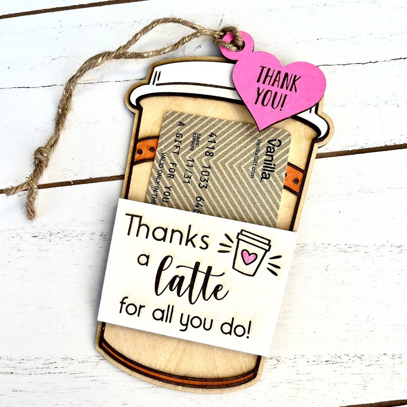 Puede incluir: Un porta tarjetas de regalo de madera en forma de taza de caf&eacute; con un coraz&oacute;n rosa que dice "&iexcl;Gracias!" y una tarjeta de regalo dentro. El porta tarjetas tiene una peque&ntilde;a taza de caf&eacute; con un coraz&oacute;n dibujado y el texto "&iexcl;Gracias por todo lo que haces!"