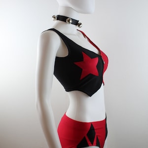 Puede incluir: Un disfraz negro y rojo con un patrón de estrella y diamante. El disfraz incluye una parte superior sin mangas y un par de pantalones cortos.