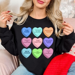 May include: Black sweatshirt with a colorful design of candy hearts featuring the names of various bands, including The Cure, Echo & The Bunnymen, The Smiths, Depeche Mode, The Jesus & Mary Chain, Siouxsie & The Banshees, The Psychedelic Furs, New Order, and Love & Rockets.