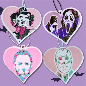 May include: Four pink heart-shaped car air fresheners with floral patterns and images of horror movie characters. The characters are Freddy Krueger, Ghostface, Michael Myers, and Jason Voorhees.