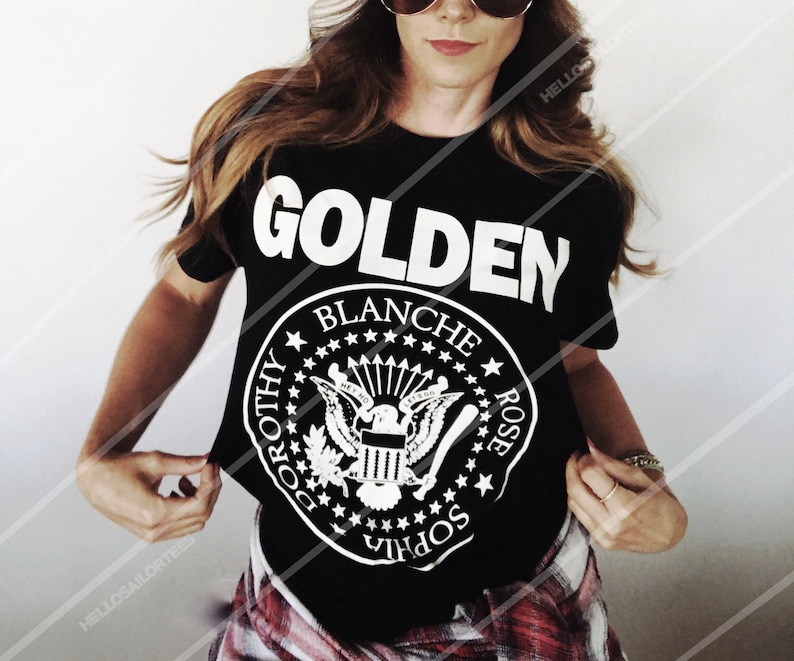 May include: Black t-shirt with a white graphic of the words "GOLDEN" and a seal with the words "DOROTHY, BLANCHE, SOPHIA, ROSE" around it.