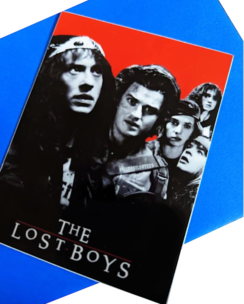 K&ouml;nnte beinhalten: Ein Schwarzwei&szlig;-Poster mit rotem Hintergrund, auf dem der Filmtitel "THE LOST BOYS" zu sehen ist. Das Poster zeigt f&uuml;nf Charaktere aus dem Film, darunter einen Vampir mit Lederjacke und eine Gruppe junger Leute.