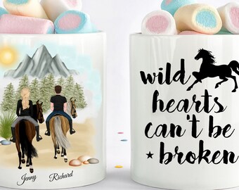 May include: Two white mugs with a couple riding horses in a mountain landscape on one mug and the text "wild hearts can't be broken" with a black silhouette of a horse on the other mug.