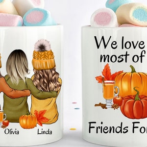 May include: Two white mugs with fall-themed designs. One mug features three women with autumn-colored clothing and the text "Victoria, Olivia, Linda". The other mug has a pumpkin, leaves, and a glass of cider with the text "We love fall most of all, Friends Forever".