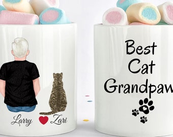 May include: White ceramic mug with a personalized illustration of a man with gray hair and a cat. The text "Larry" and "Zari" are printed on the mug. The other side of the mug has the text "Best Cat Grandpaw" with three paw prints.