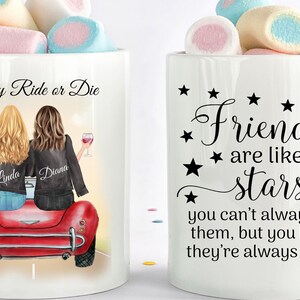 May include: Two white ceramic mugs filled with marshmallows. One mug features an illustration of two friends in a red car with the text "My Ride or Die." The other mug has the text "Friends are like stars."