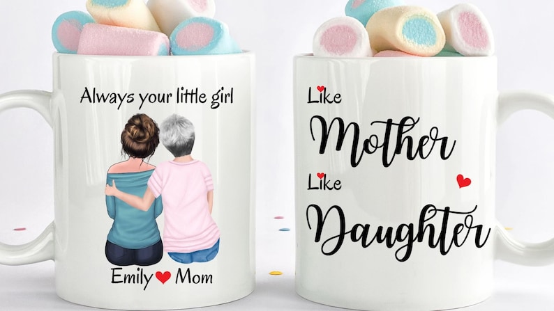 May include: Two white coffee mugs with a design of two women, one with brown hair and one with gray hair, with the text "Always your little girl" and "Emily &hearts; Mom" on one mug and "Like Mother Like Daughter" on the other mug.