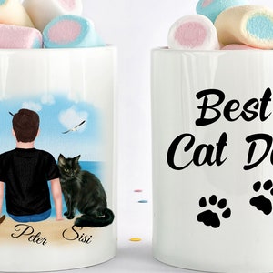 May include: White ceramic mug with a black and white design. The mug has a picture of a person with two cats on the front and the text "Best Cat Dad" with two paw prints on the back.