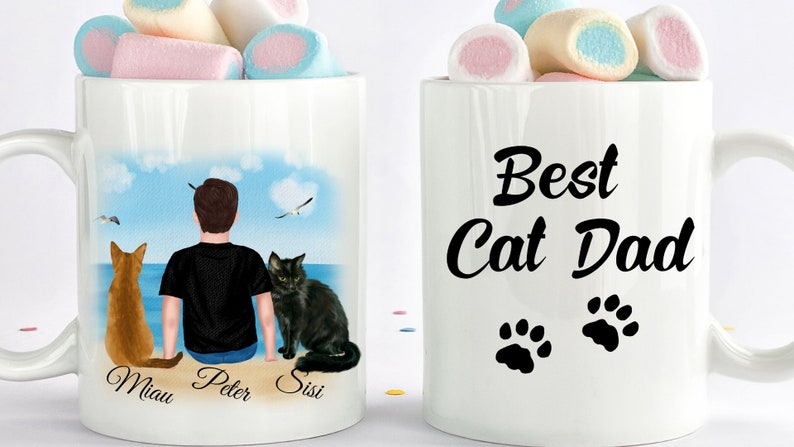 May include: White ceramic mug with a black and white design. The mug has a picture of a person with two cats on the front and the text "Best Cat Dad" with two paw prints on the back.