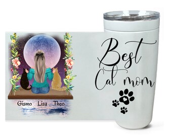 May include: White tumbler with a black design that says "Best Cat Mom" with three paw prints below the text. The paw print in the center has a heart in it. The tumbler has a lid.  The image also shows a white background with a colorful illustration of a woman with two cats sitting on a swing under a large moon.