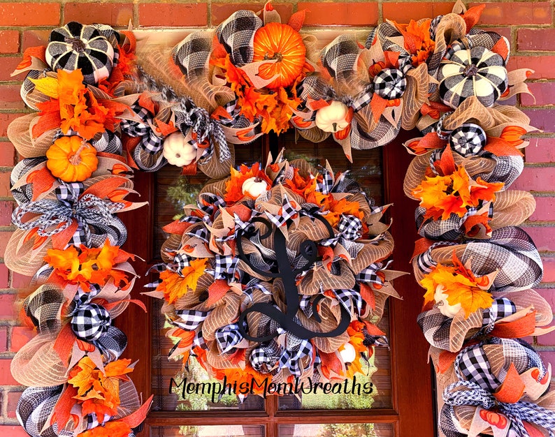 Puede incluir: Un conjunto de corona y guirnalda oto&ntilde;al para puerta con calabazas naranjas, cintas de cuadros negros y blancos y malla color canela. La corona circular incluye una letra L grande en cursiva negra en el centro. Texto MempisMomWreaths visible.