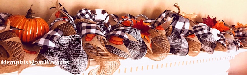 Puede incluir: Una guirnalda decorativa con calabazas naranjas, tela de cuadros negros y blancos y bucles de malla de arpillera de color tostado natural. El arreglo incluye hojas de oto&ntilde;o artificiales y el texto MemphisMomWreaths en la parte inferior izquierda.