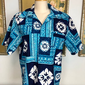 May include: A blue and white Hawaiian shirt with a geometric pattern and floral designs. The shirt has a short sleeve and a collared neckline.