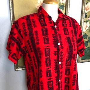 1950er Jahre Herren Baumwolle Hawaiian Shirt-- Fett Tiki polynesischen Design gegen einen lebendigen roten Hintergrund