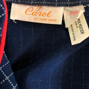 May include: A navy blue checked fabric with a white label that reads "Lady Carol of New York" and a white label that reads "Polyester, tumble dry, require touch-up ironing".
