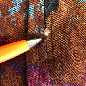 May include: Close-up of a brown, black, and blue patterned fabric with a seam down the center. The fabric has a textured, woven look.