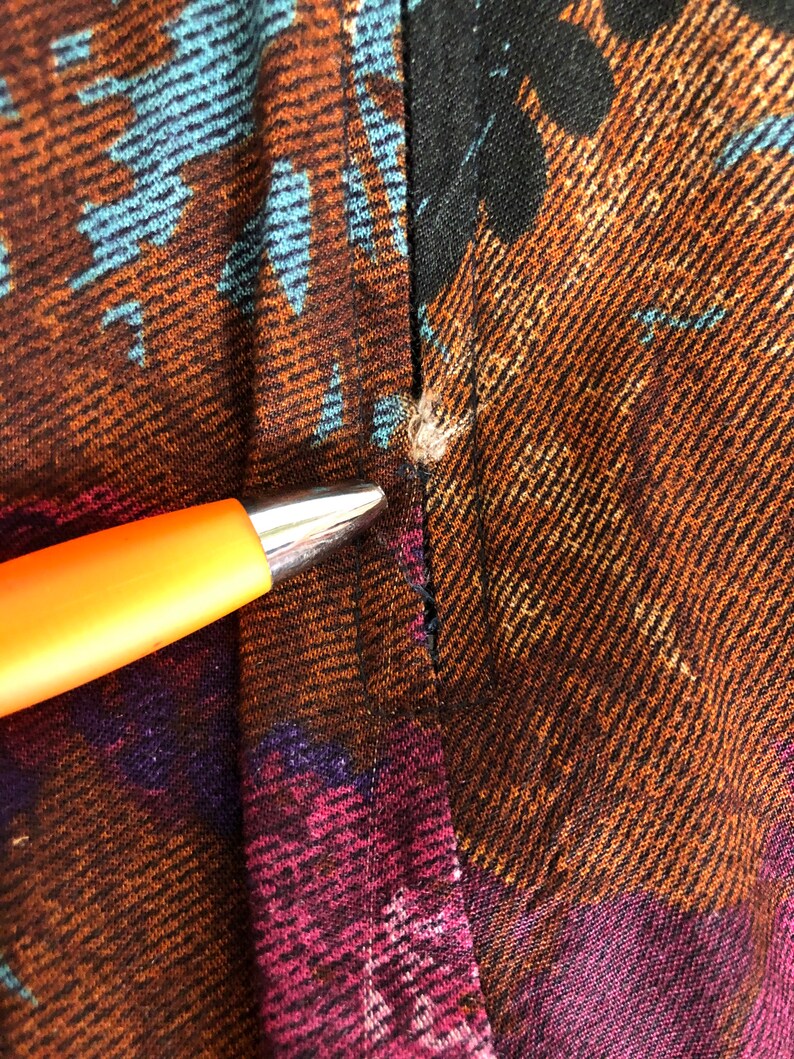 May include: Close-up of a brown, black, and blue patterned fabric with a seam down the center. The fabric has a textured, woven look.