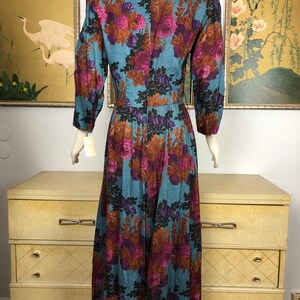 May include: A long, blue dress with a floral print featuring pink, purple, and brown flowers. The dress has a v-neck and long sleeves.