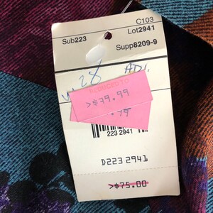 May include: A white tag with black text and a pink tag with black text. The white tag says "Sub223", "C103", "Lot2941", "Supp8209-9", "D223 2941", and "$75.00". The pink tag says "REDUCED TO", "$79.99", and "28".