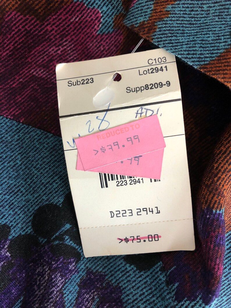 May include: A white tag with black text and a pink tag with black text. The white tag says "Sub223", "C103", "Lot2941", "Supp8209-9", "D223 2941", and "$75.00". The pink tag says "REDUCED TO", "$79.99", and "28".