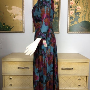 May include: A teal blue midi dress with a floral print in shades of brown, pink, and purple. The dress has a V-neckline and 3/4 sleeves.
