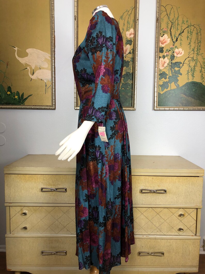 May include: A teal blue midi dress with a floral print in shades of brown, pink, and purple. The dress has a V-neckline and 3/4 sleeves.