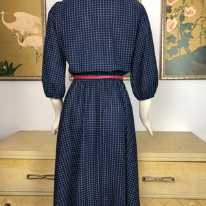 May include: A navy blue and white gingham dress with a red belt. The dress has a collared neckline and 3/4 sleeves.