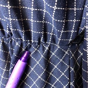 May include: Close-up of a navy blue fabric with a white grid pattern. The fabric has a slight texture and is slightly wrinkled.